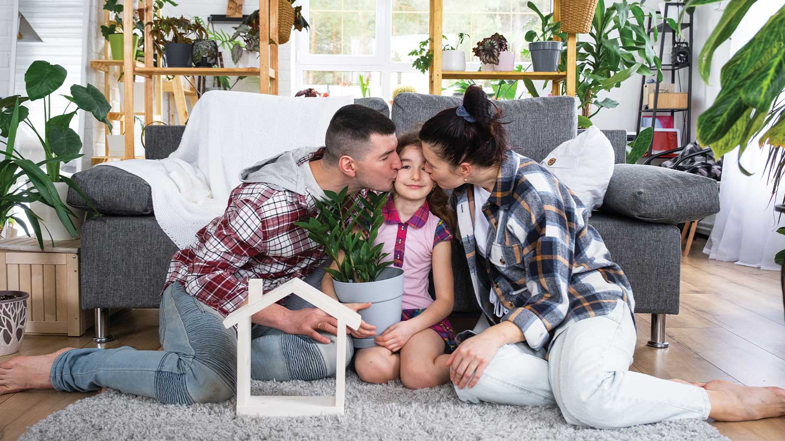 Family embracing cozy living space with greenery, showcasing interior design tips for every season.