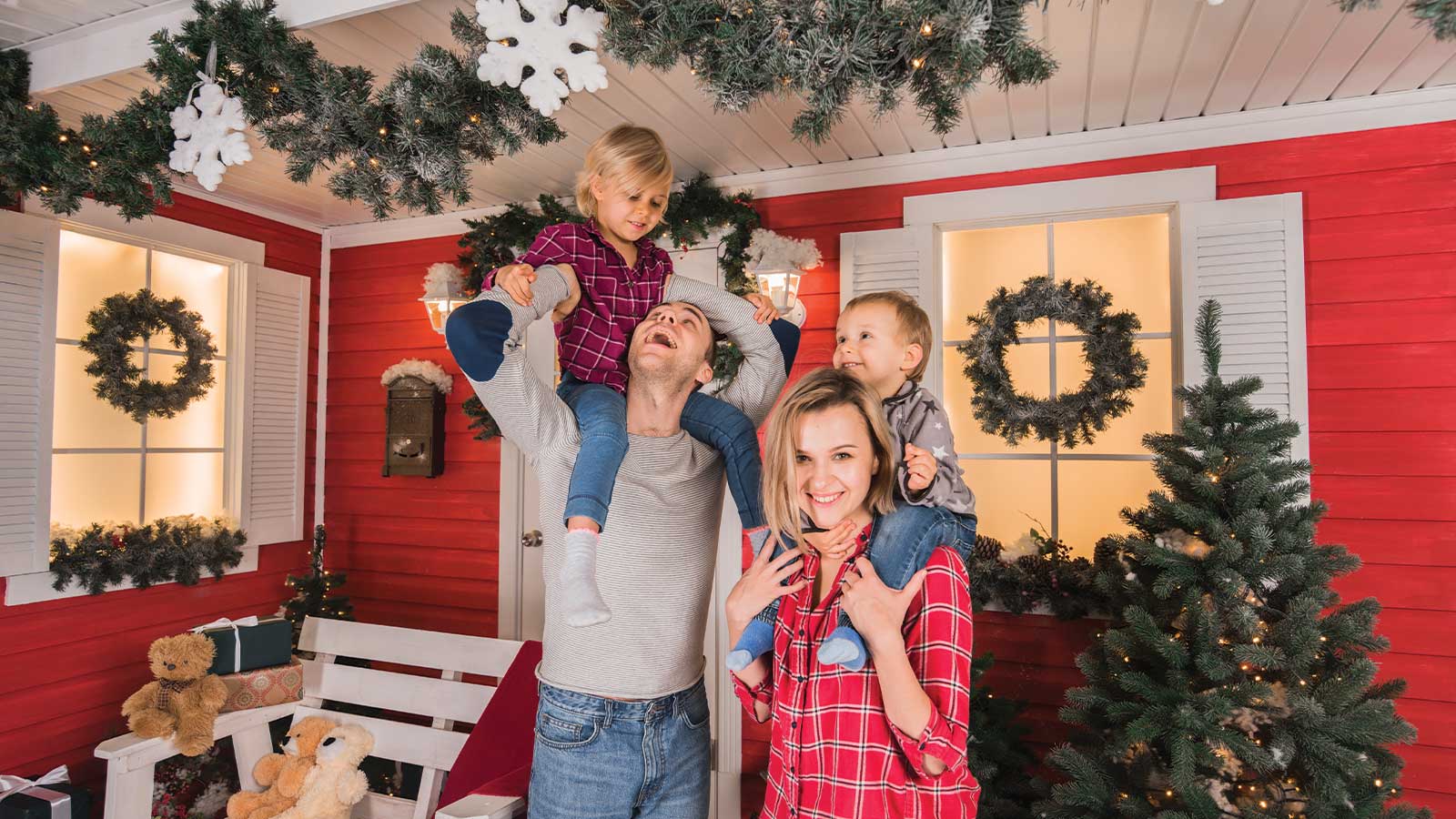 A happy family enjoying festive year-round décor with wreaths, garlands, and a beautifully decorated red exterior in the Lower Mainland.