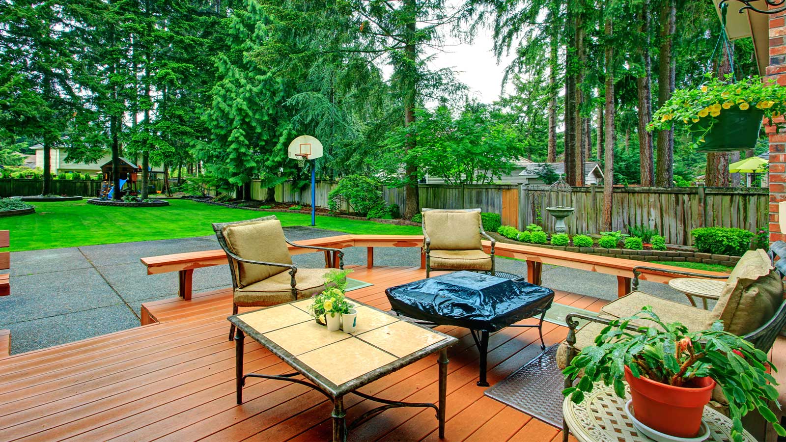 A beautifully maintained wooden deck with cozy patio furniture surrounded by lush greenery, showcasing the results of expert deck staining in Vancouver for outdoor spaces.