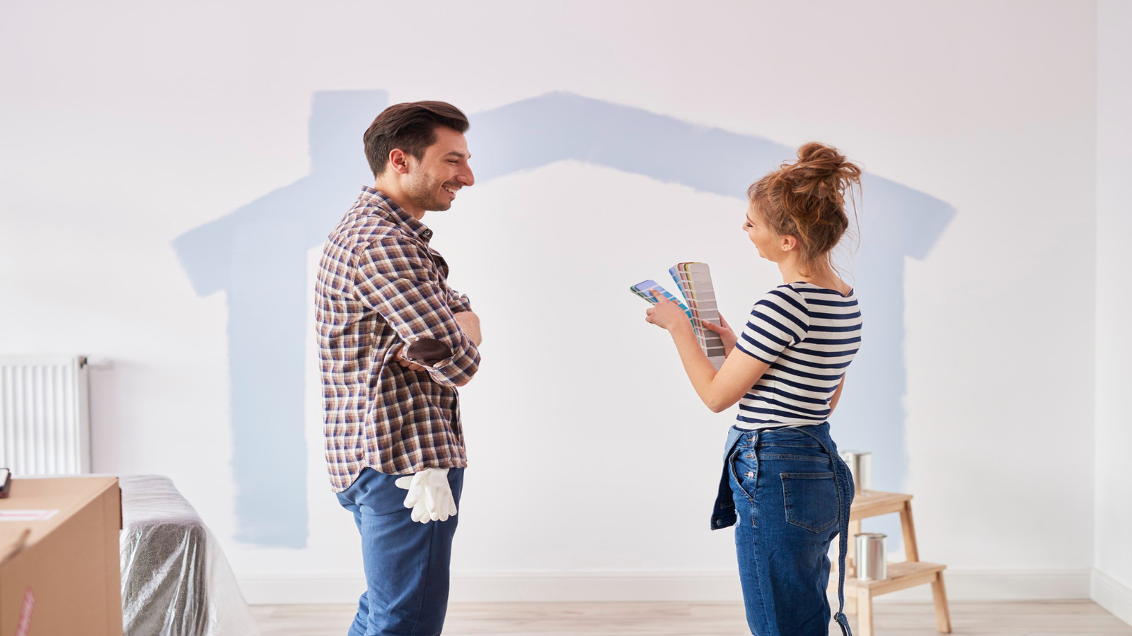 Roarty Painting captures Warm Tones vs Cool Tones: What Works Best in Vancouver Homes as a couple compares swatches on a wall shaped like a house.