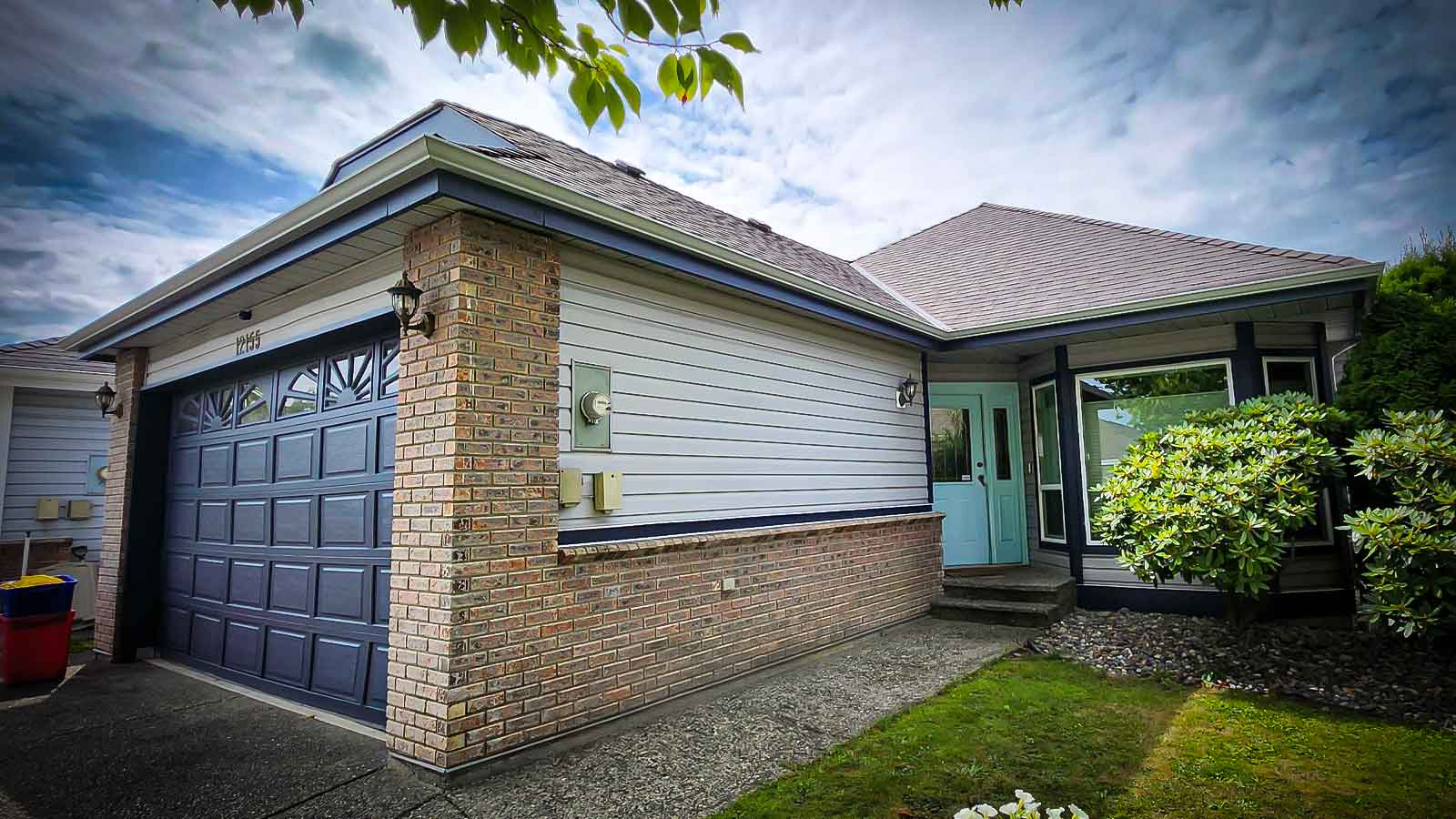 Rancher style home with blue garage door on a sunny day.