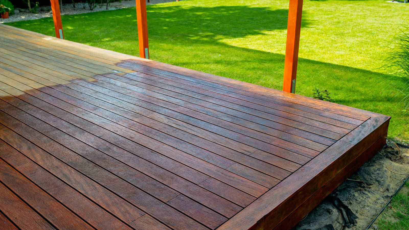 Close-up of a wooden deck - on the covered terrace - showing the process of restoration with a half-stained surface contrasting weathered and treated wood during a home improvement project